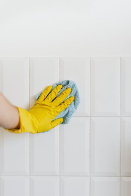 A person wearing brown cleaning gloves is placing a lightbox sign with the words 'CLEANING HOME' in bold black letters on a white background, illuminated from within. The sign is situated on a flat su